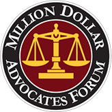 Logo of the Million Dollar Advocates Forum featuring gold scales of justice on a maroon background encircled by a black ring with the organization's name in white text.